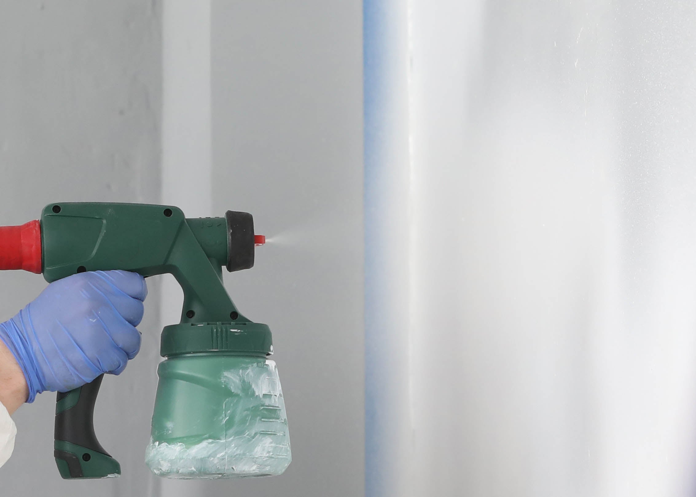 spraying our white peelable solvent based paint on to a wall 